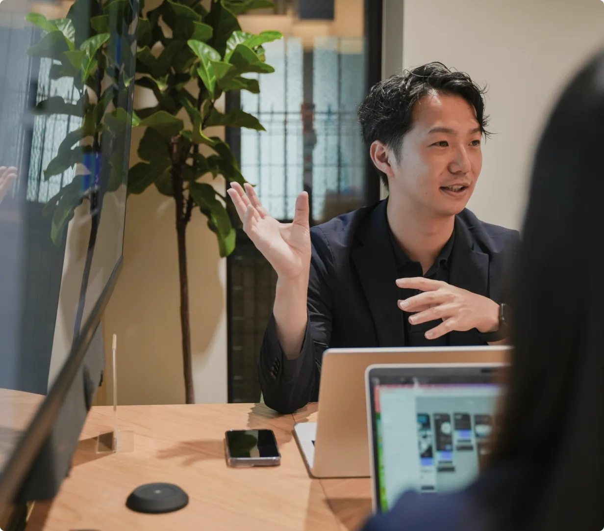 ミーティングで身振りを交えて話すメンバー