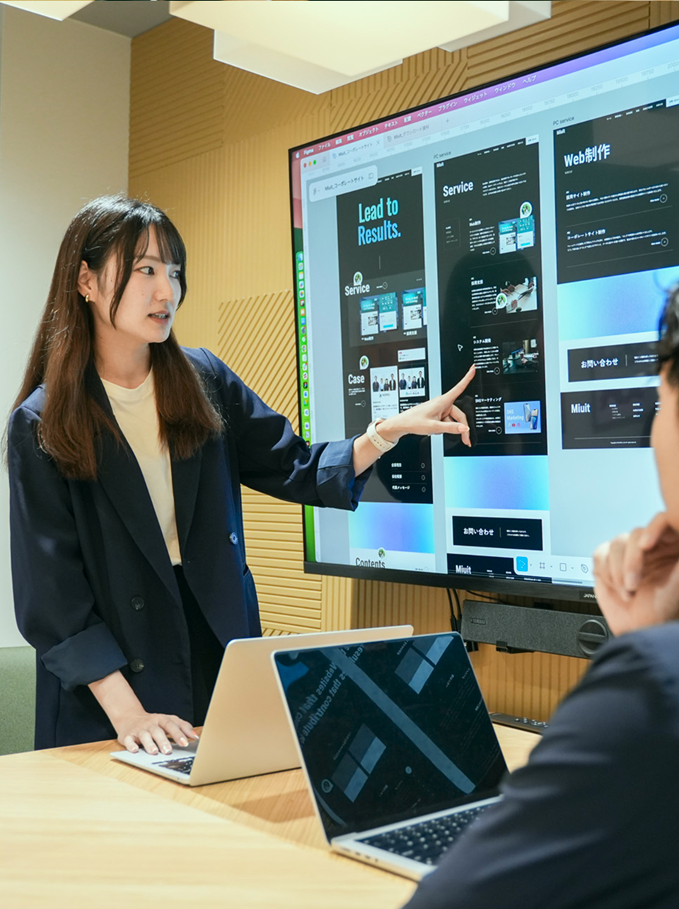 モニターに映したWebサイトのデザインを指し示しながら説明する Miuit のメンバー